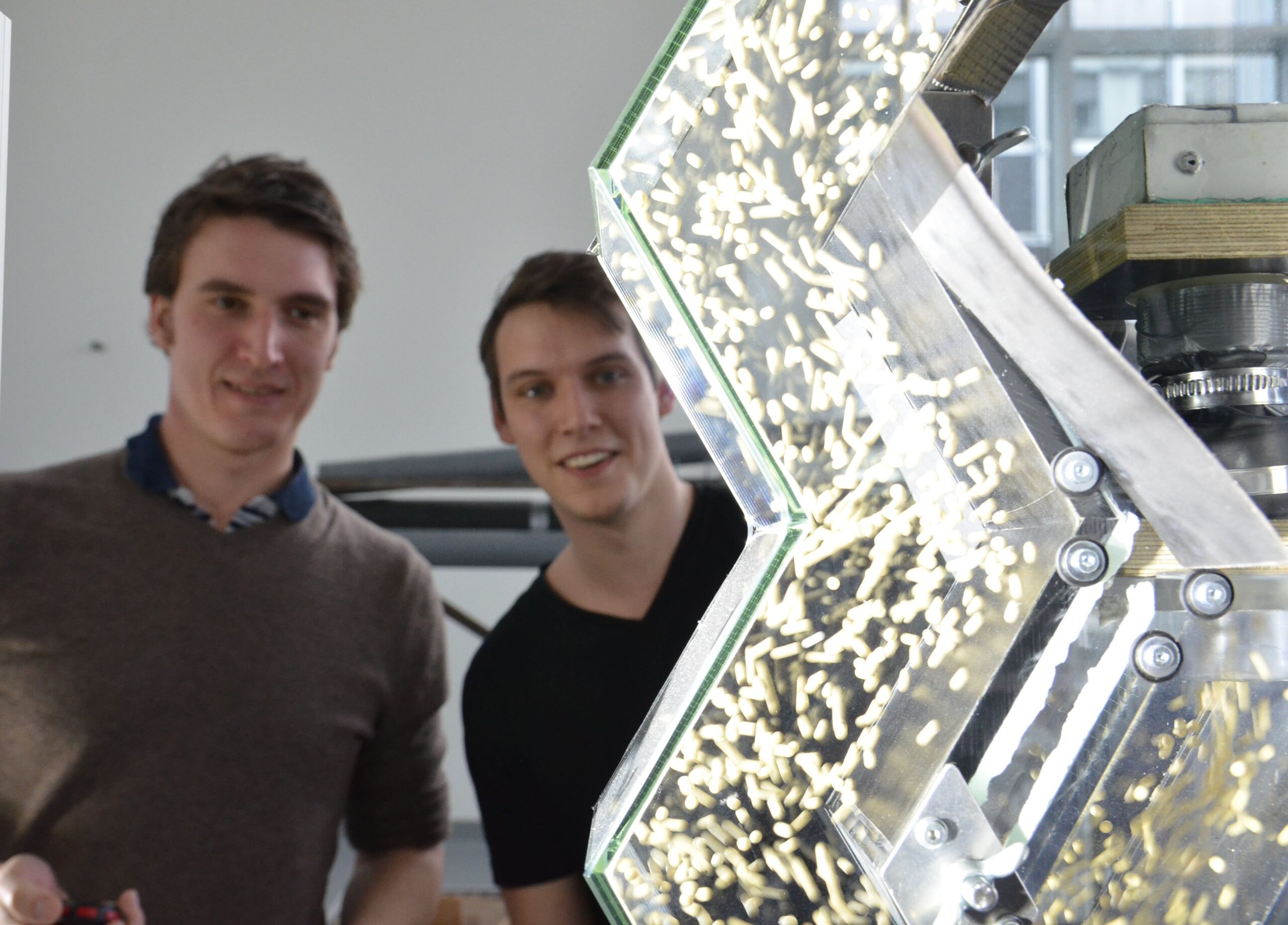 Die Modellpartikel werden von der Luftströmung durch den selbst gebauten, transparenten Zick-Zack-Sichter geschleppt. Um die chaotische Bewegung der Partikel analysieren zu können, erfassen Sebastian Bartscher (l.) und Simon Schepers sie mit dem 3D Particle-Tracking-Velocimetry Verfahren. (Foto: FH Münster/Pressestelle)