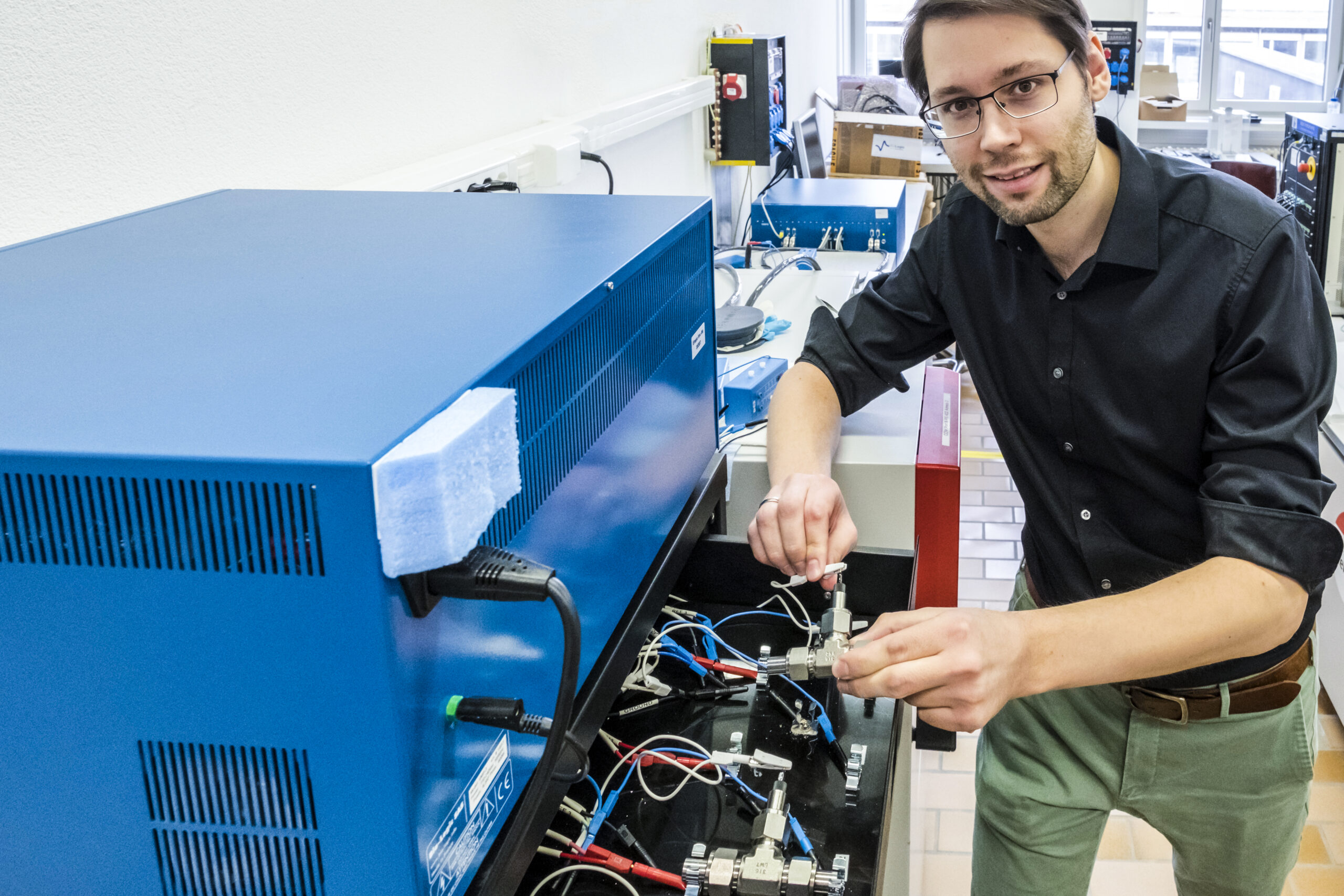 Batterieforschung: Ruben Simon Kühnel forscht an wässrigen Elektrolyten für künftige Lithium-Ionen-Zellen. Hier platziert er Versuchszellen in ein Messgerät, um sie wiederholt zu laden und zu entladen