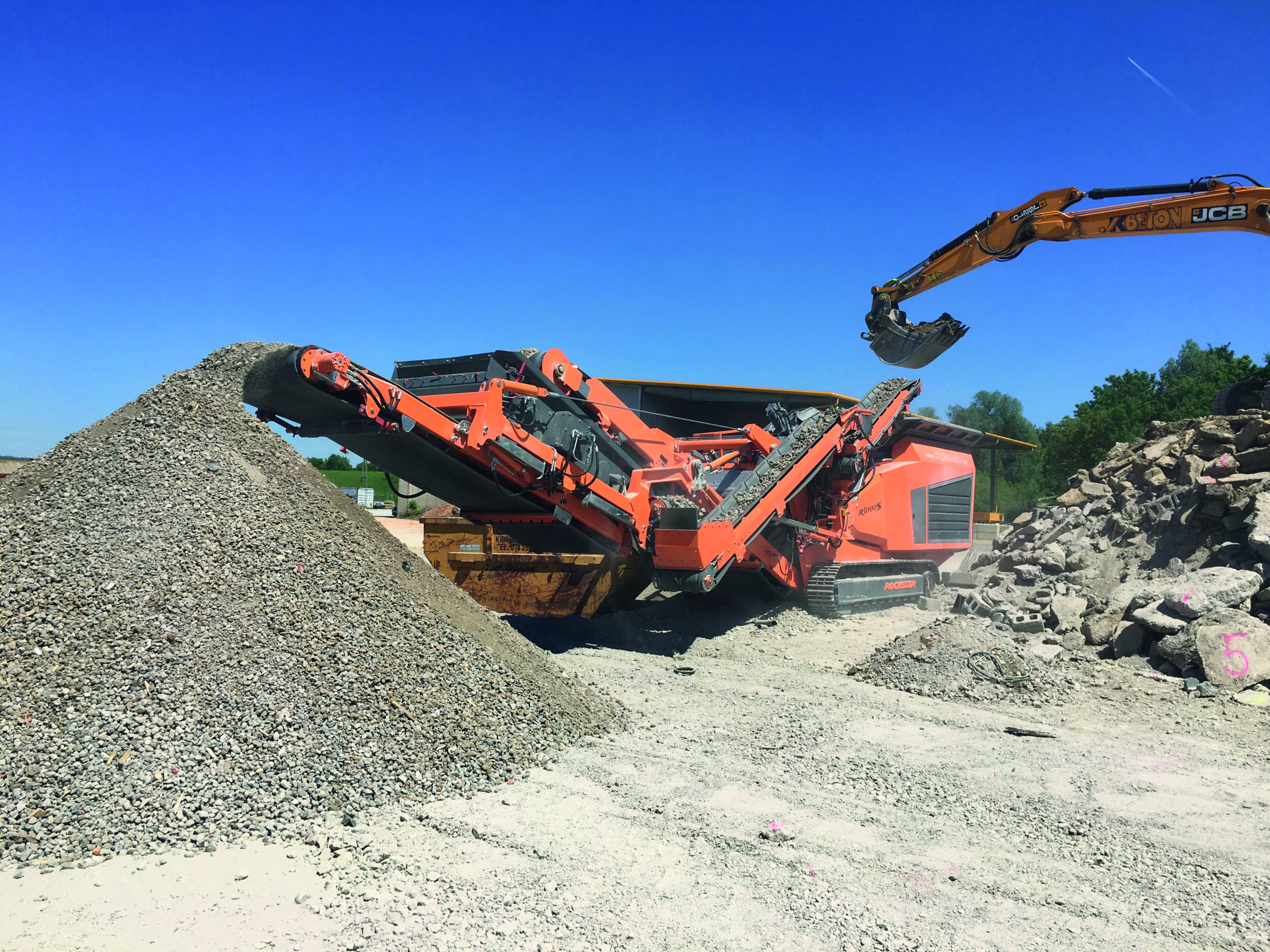 Der neue Rockster R1000S inkl. kompakten Kreisschwingsieb RS100 und patentrechtlich geschützten Rückführband RB92 beim Brechen von Beton.