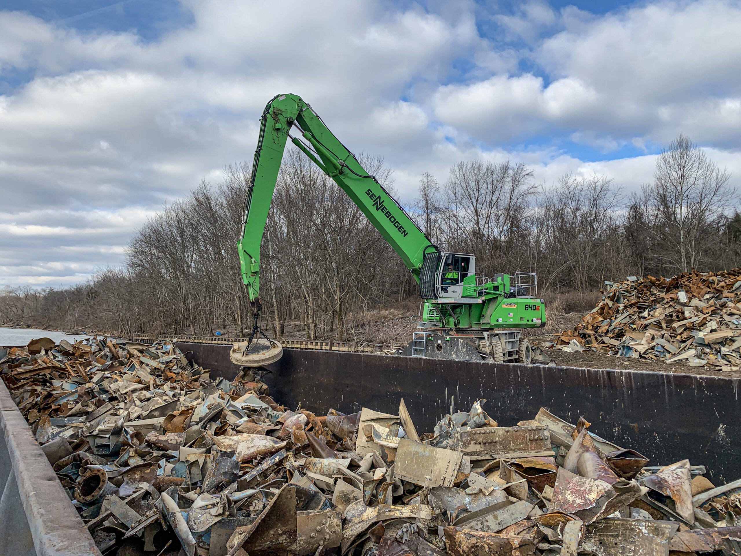 Der Sennebogen 840 E in der Mobilvariante unterstützt nun mit Magnet Adamo Demolition in den USA beim Extrahieren von Metallschrott aus Bauschutt und verlädt diesen in Lastkähne. Bild: Sennebogen LLC