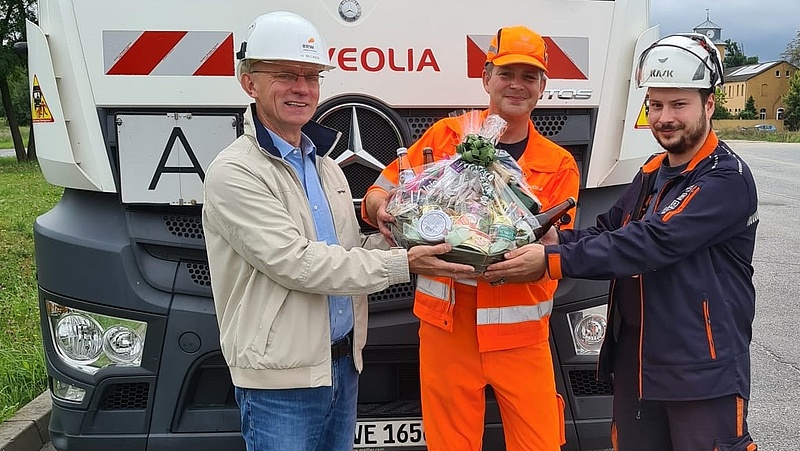 Heinz Becker (li), EEW Vertrieb Ost, und Stefan Schröder, Tagschichtleiter EEW Großräschen, überreichen Andreas Müller, Kraftfahrer Veolia Umweltservice, einen Präsentkorb. Er lieferte am 30. August um 12.30 Uhr Ersatzbrennstoffe an und überschritt mit seiner Ladung die Schwelle zur 3-millionsten Tonne Abfallverwertung im Kraftwerk Sonne. Bild: EEW 2021