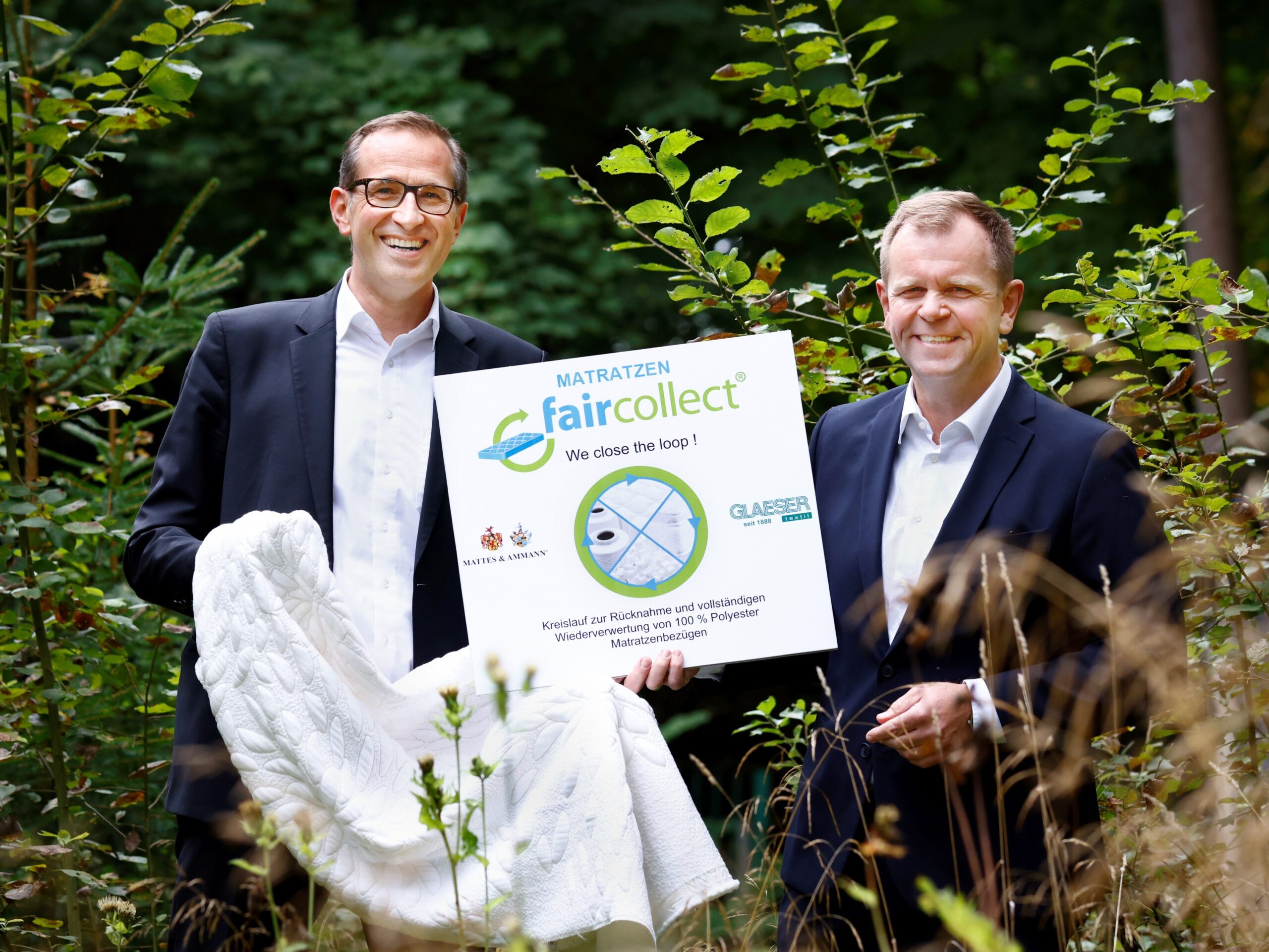 Eberhard Brack (Märkische Faser) und Werner Moser (M&A) mit Logo und Textil der faircollect-Serie – Bild: Alexander Kaya