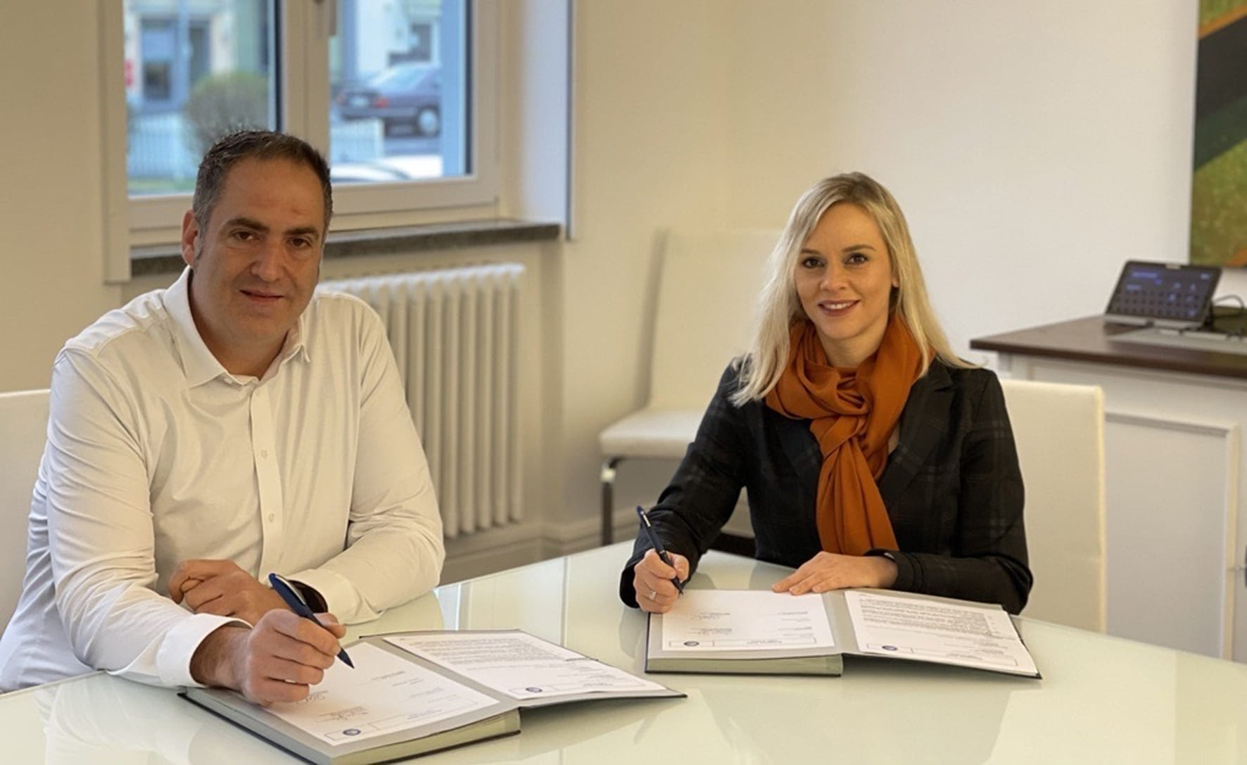 Thore Lapp, Leiter der Business Unit Green Energy & Sustainability von TÜV SÜD, und Sabrina Goebel, Geschäftsführerin der RecycleMe GmbH, bei der Unterschrift.