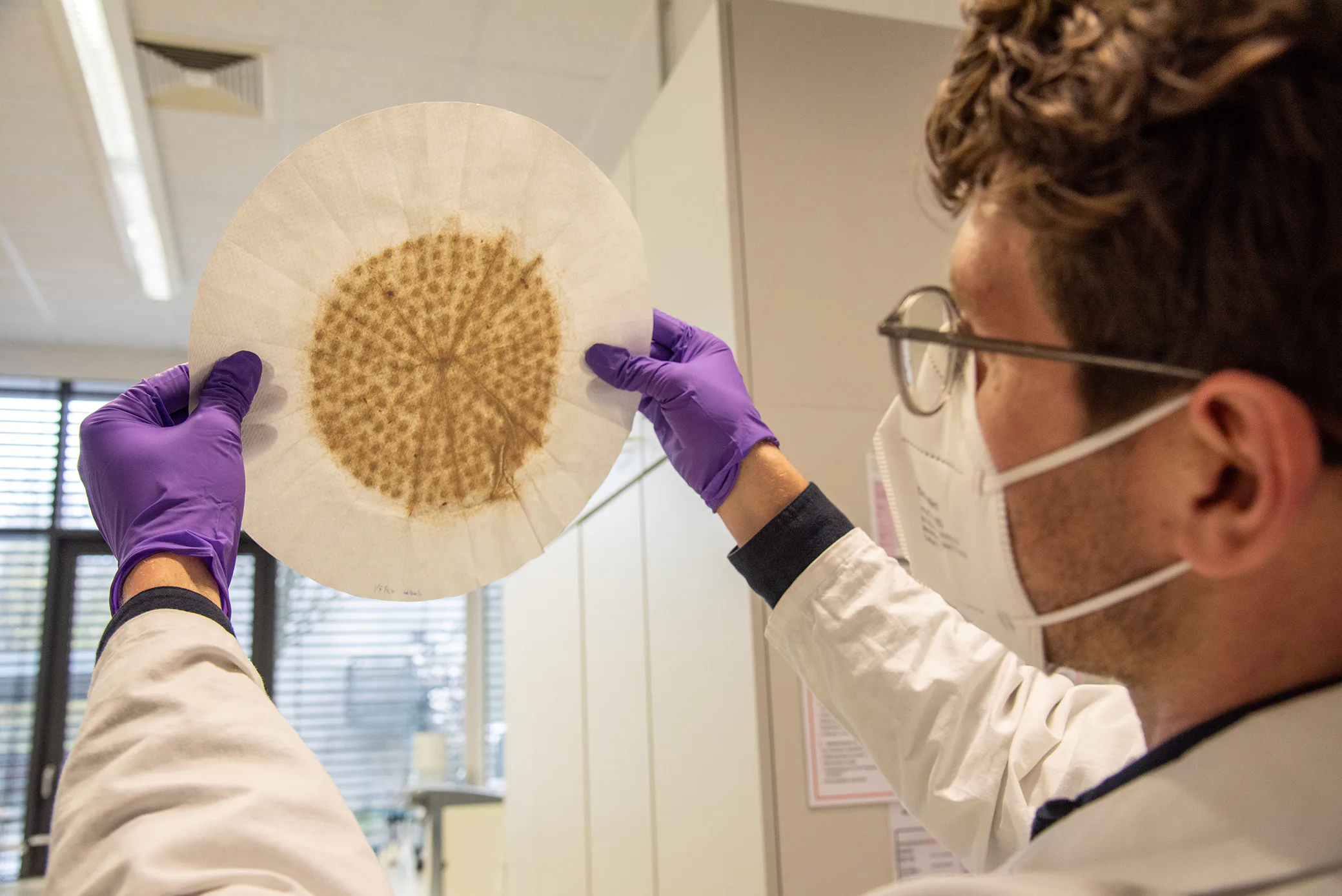 Hat sich der Karton aus den Gipskartonplatten ausreichend im Wasser aufgelöst? Das prüft Promovend Wojciech Walica mit Blick auf das Filterpapier – ein Testschritt auf dem Weg zur Herstellung von Gipsfaserplatten aus Recyclingmaterial. Bild: FH Münster/Michelle Liedtke