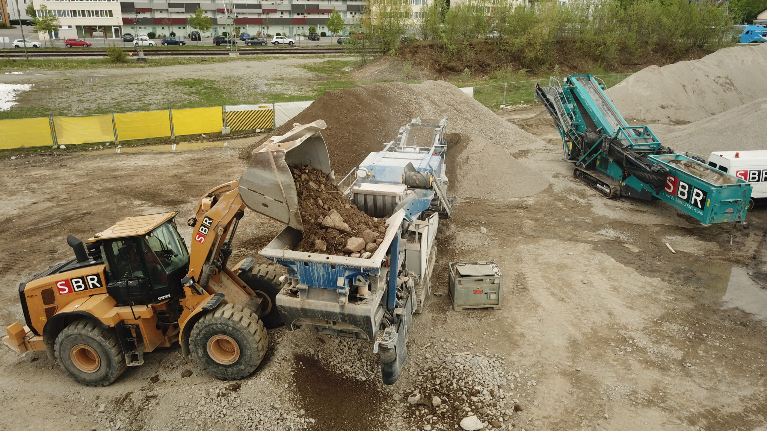 Ein Bagger befüllt den Prallbrecher auf dem unweit gelegenen Zwischenlager. Bild: Georg Reisch GmbH & Co. KG