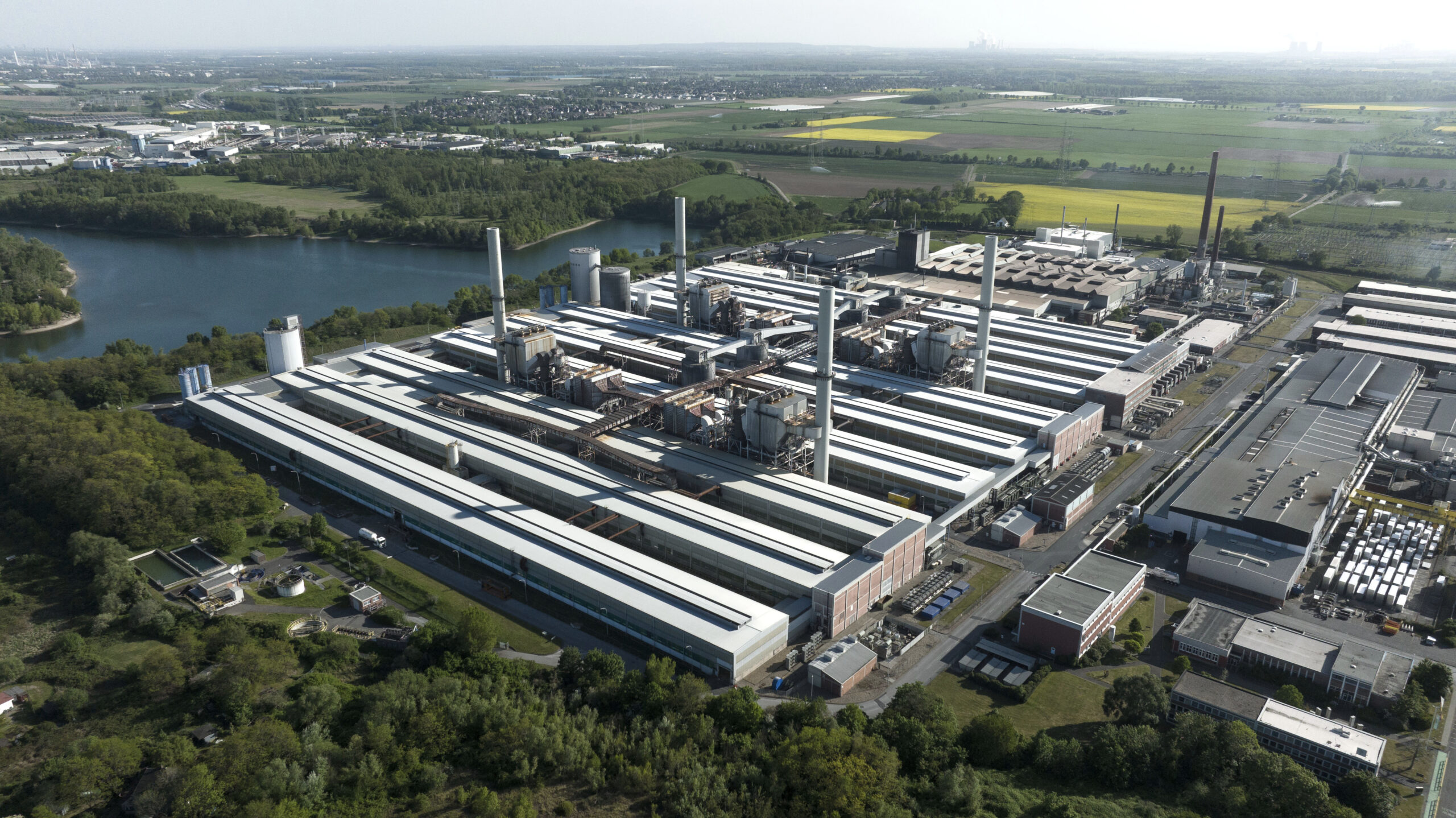 Rechts die Gießerei, in der der neue Ofen errichtet wird, vorne links die drei Hallen der heruntergefahreren Aluminiumhütte, die nun teilweise für neue Lagerflächen und die Beprobung genutzt werden sollen. Copyright: Speira