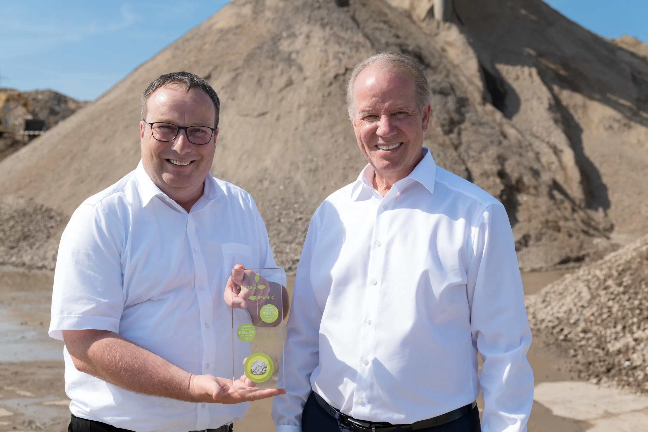 NRW-Umweltminister Oliver Krischer und Remex-Geschäftsführer Michael Stoll: In der Remex-Recyclinganlage werden aus Boden und Bauschutt güteüberwachte Recyclingbaustoffe hergestellt, deren Nutzung im Tiefbau seit Jahrzehnten etabliert ist. Ein Teil dieser Recyclingbaustoffe könnte problemlos auch im Hochbau eingesetzt werden. Copyright: Remex