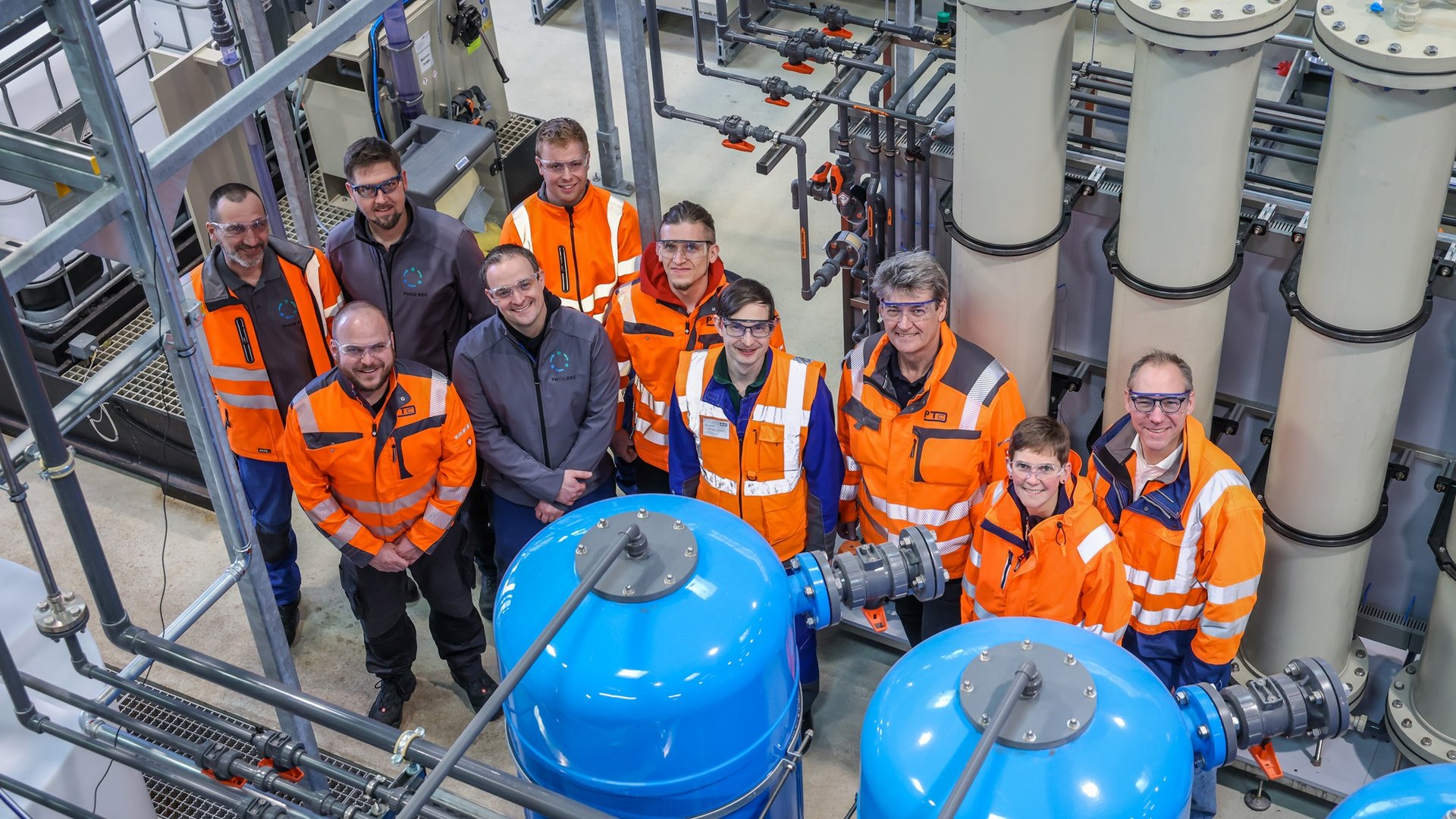 Die verantwortlichen Akteurinnen und Akteure zwischen den Ionenaustauscher-Stufen der Rückgewinnungsanlage: (v.L.n.r.) Carsten Bräuer, Dr. Dennis Blöhse, Fabian Rovers (alle EG/PhosRec), Christoph Thiel (PTC), Willi Markwart (EG/PhosRec), Andre Bends, Dr. Reinhard Lohmeier, Jürgen Waller (alle PTC), Dr. Yvonne Schneider (RV/PhosRec), Prof. Torsten Frehmann (EG/PhosRec). Copyright: ELGV / Rupert Oberhäuser