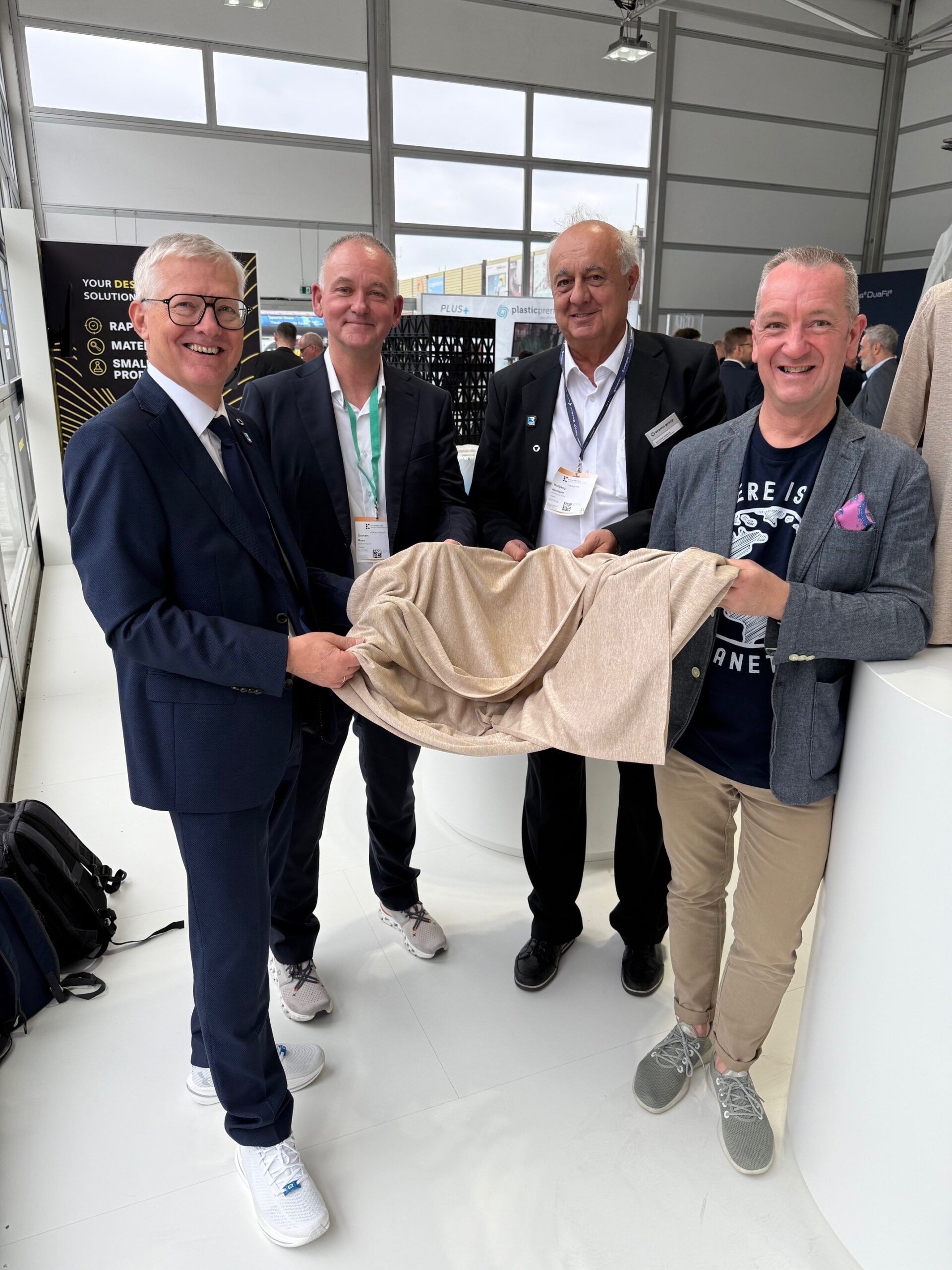 Von links: Manfred Hackl (Erema Group), Graham Ross (BlockTexx), Wolfgang Hermann (Erema Group) und Adrian Jones (BlockTexx) mit dem neuen Gewebe aus 100 % recyceltem Polyester im Edvanced Recycling Center. Copyright: Erema Group
