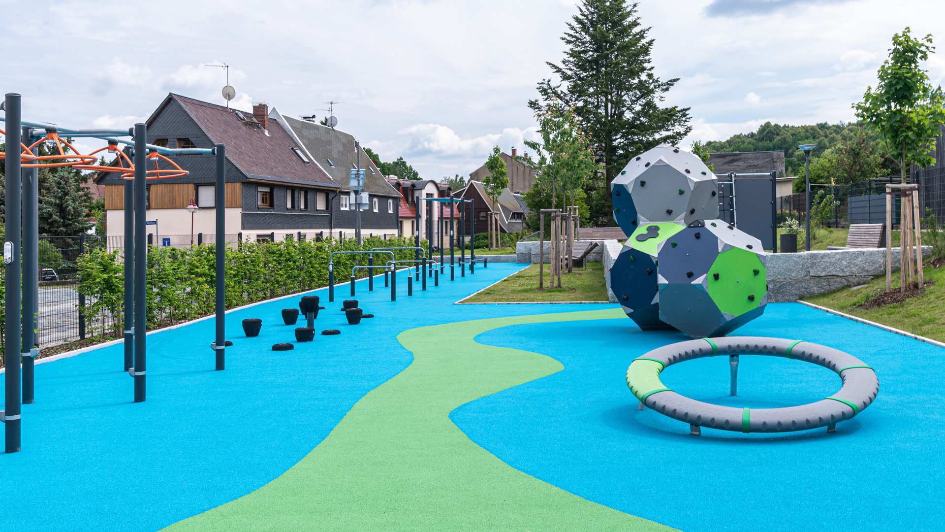 Fugenloser Fallschutzboden aus Reifen-Gummigranulat auf einem öffentlichen Spielplatz: Die zweifarbige Gestaltung in Blau und Grün zeigt die Möglichkeiten zur kreativen Flächengestaltung. Der gebundene Belag schafft eine ebene, barrierefreie Oberfläche. (Quelle: New Life)